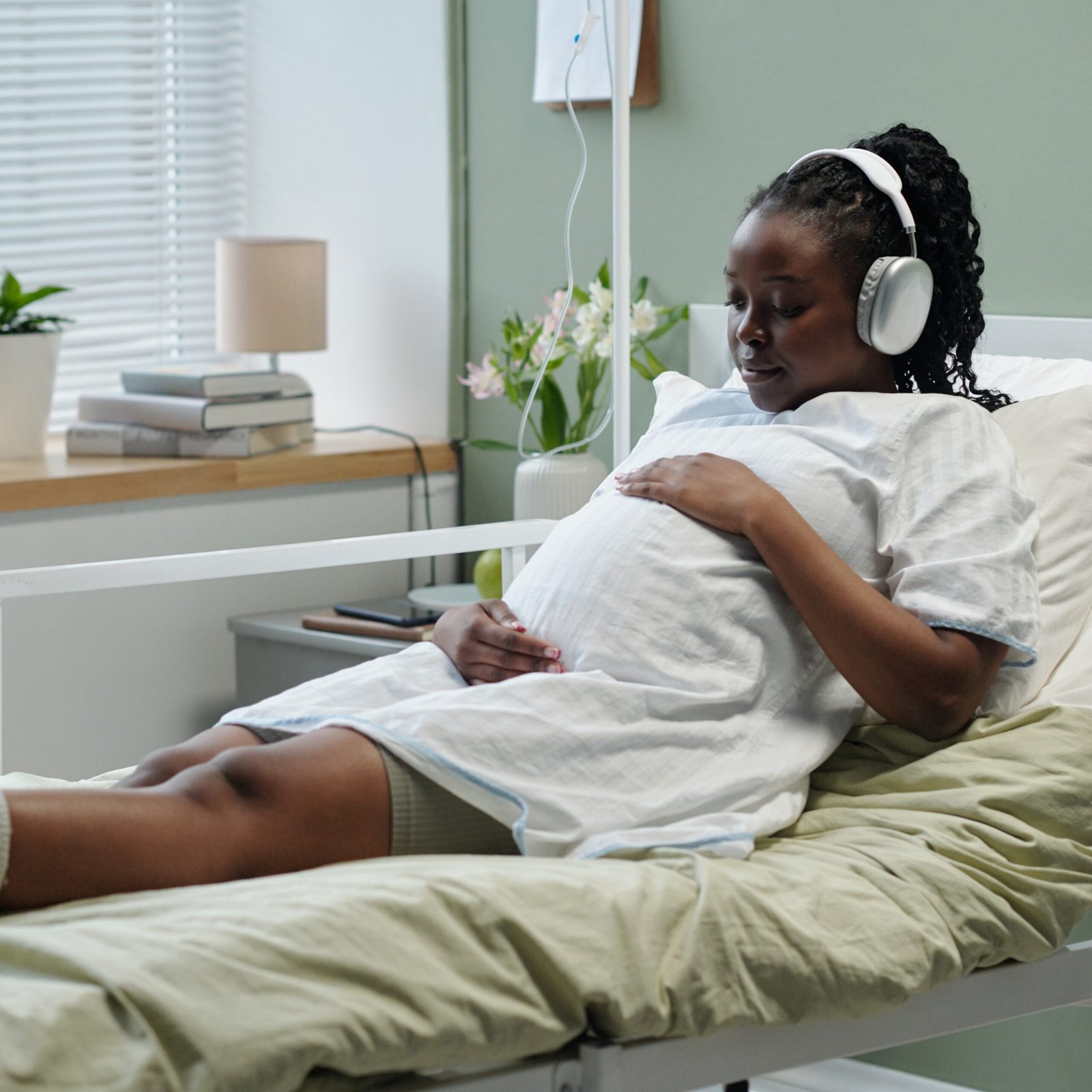 Pregnant woman reclining on a hospital bed listens to a hypnosis track through headphones