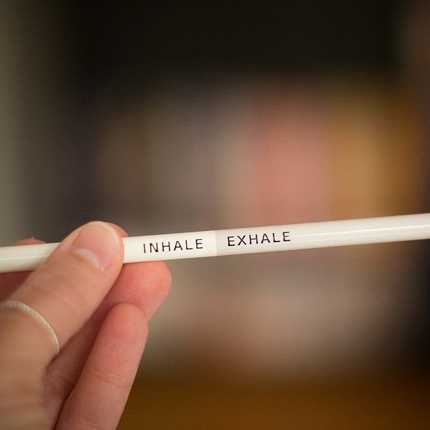 A hand holding a pencil which has inhale on one side and exhale on the other