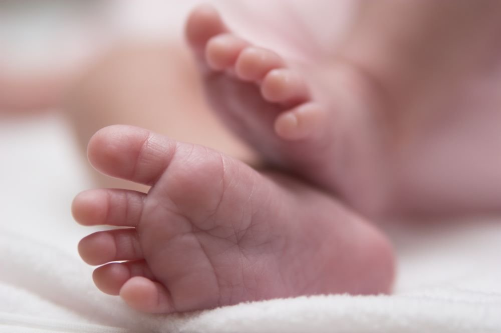 A close up photograph of the feet of a newborn baby