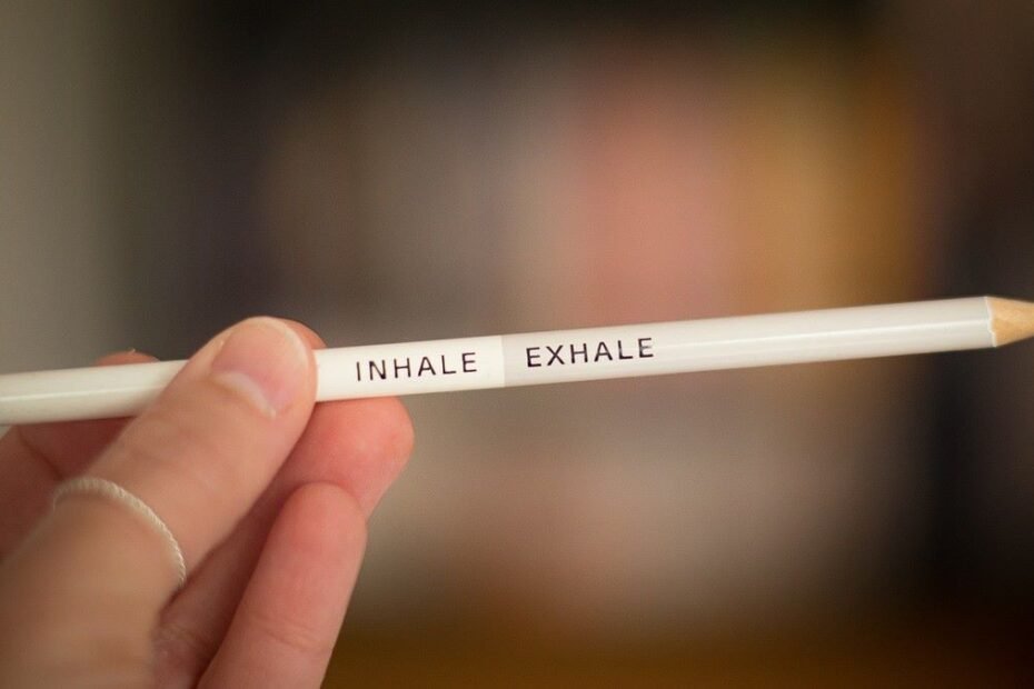 Hand holding a double-ended pencil with the words inhale and exhale on it